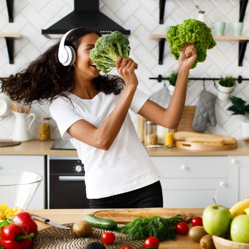 A lady dancing with salad leaves and broccoli on the modern kitchen