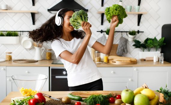 A lady dancing with salad leaves and broccoli on the modern kitchen
